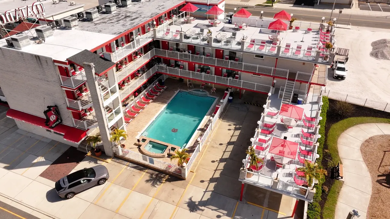 Aerial view of the Matador's heated pool and kids' wading pool in the courtyard, ringed by red loungers and red umbrellas on the sundecks
