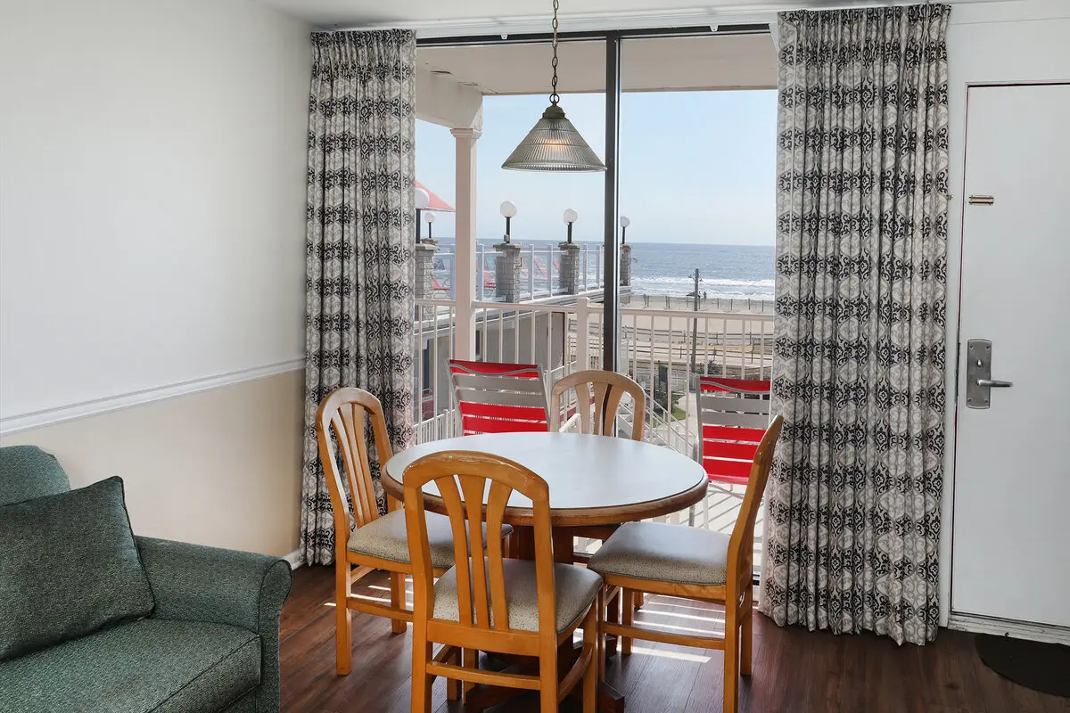 The dining table beside the balcony doors in an ocean-view unit at the Matador, red loungers on the balcony and the Atlantic beyond