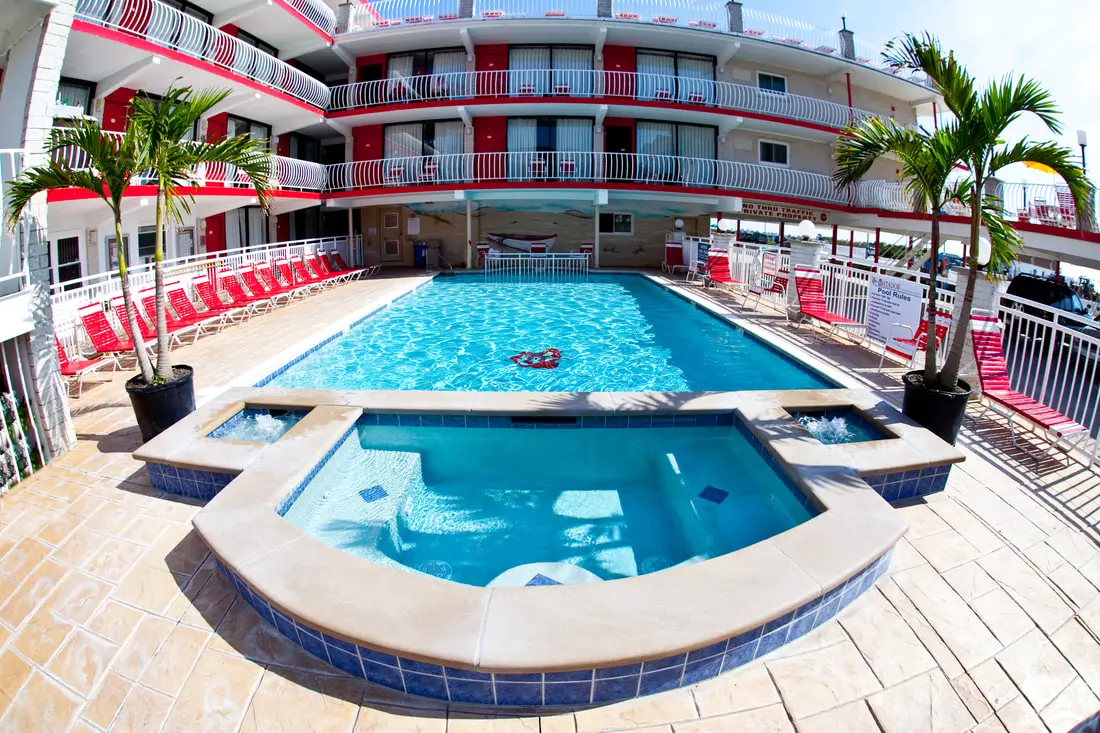 The Matador's heated outdoor pool with the adults-only spa tub in the foreground, red loungers and potted palms along the deck below the balconies