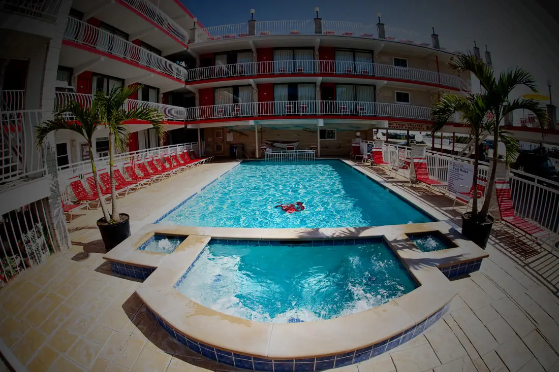 The heated pool at the Matador Oceanfront Resort, with red loungers along the deck and guest balconies rising above it