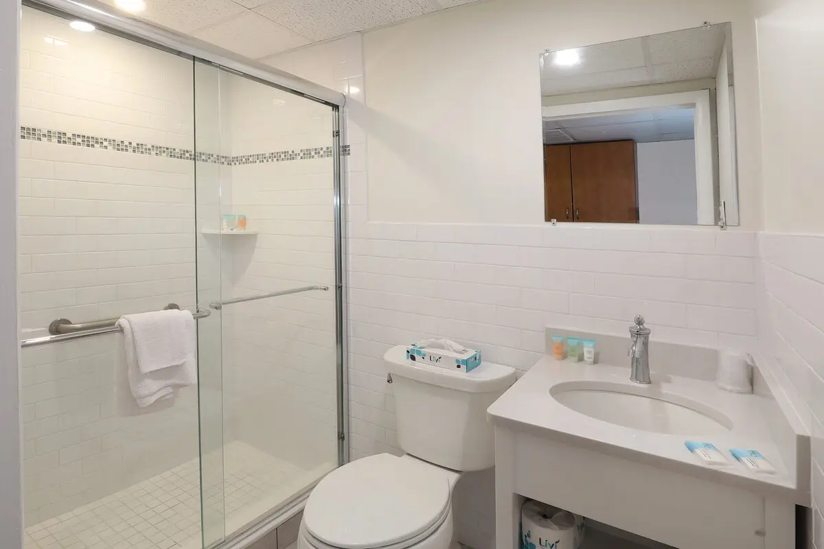 A renovated guest bathroom at the Matador with a glass walk-in shower, grab rail and vanity