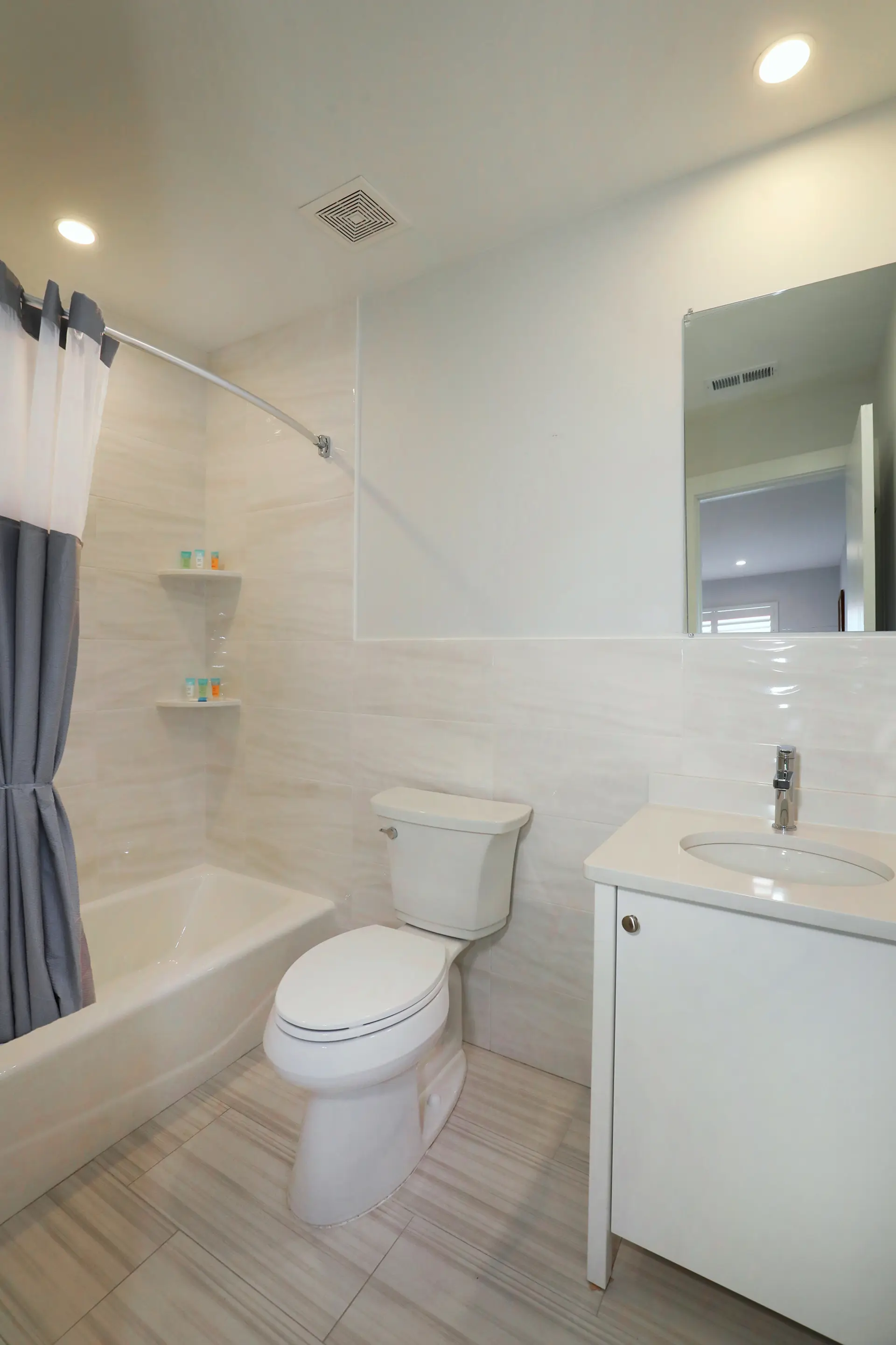A renovated guest bathroom at the Matador with a shower over the bath, tiled walls and a vanity