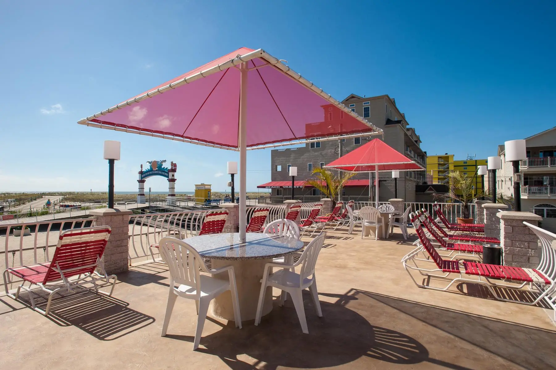 Red loungers and a red umbrella on the Matador sundeck, looking out over the North Wildwood boardwalk arch to the ocean