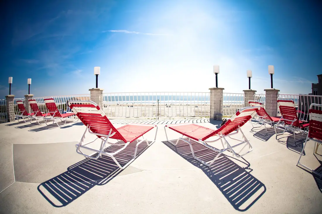 Red-and-white striped loungers arranged on the Matador oceanfront sundeck under a clear blue sky, with the beach beyond the railing