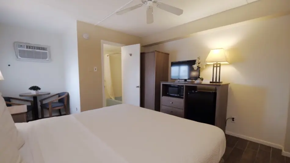 Type 1 Deluxe Motel Room at the Matador: a queen bed, small table with two chairs, microwave and refrigerator, and a ceiling fan
