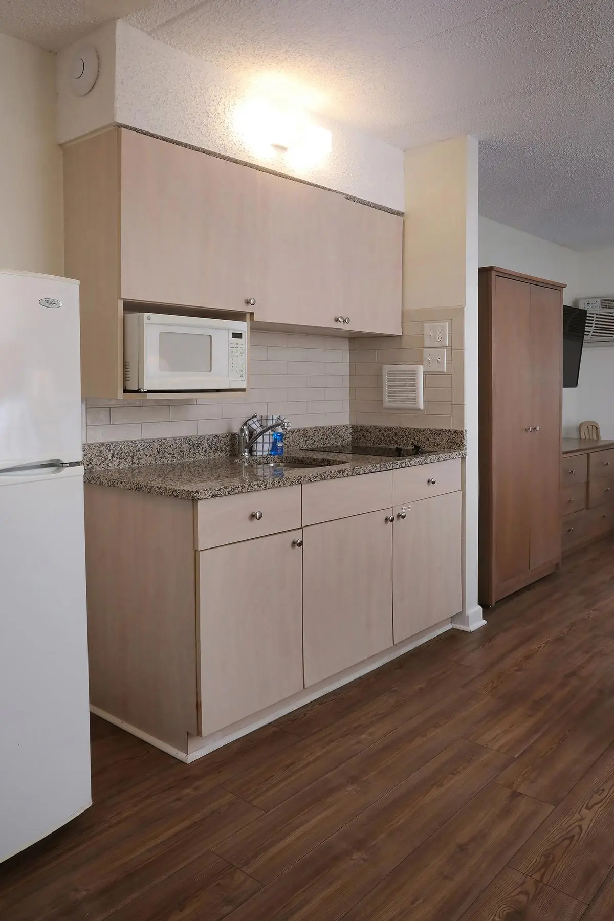 The kitchenette in a Type 3 efficiency at the Matador, with a cooktop, refrigerator, microwave and cabinets