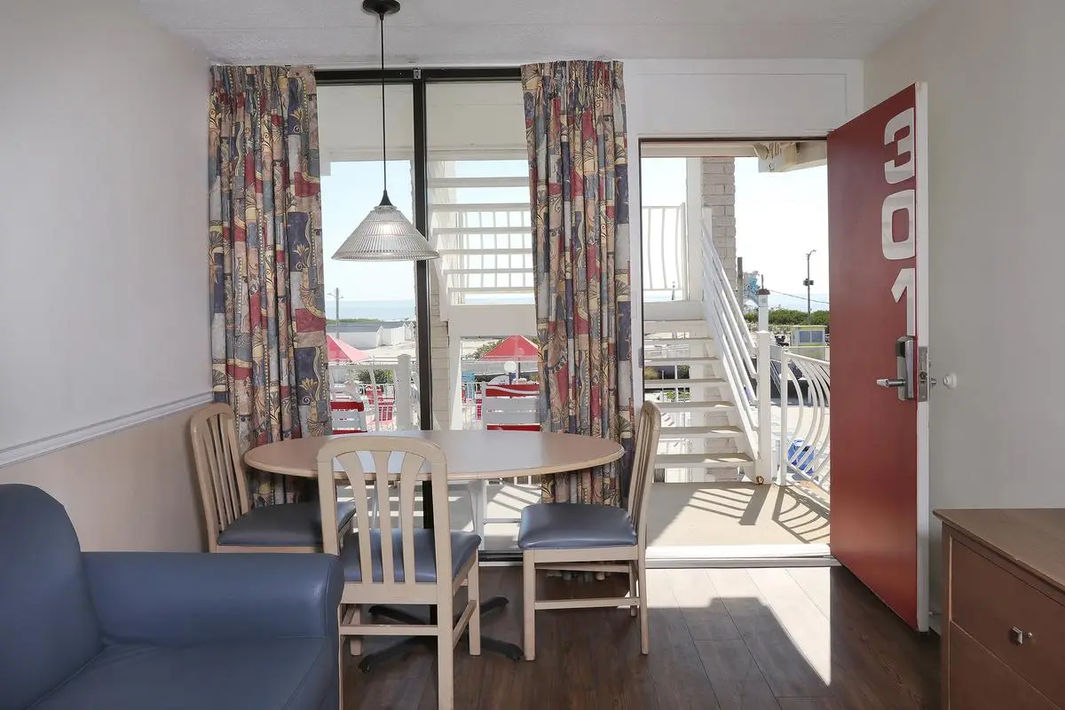 The living room of a Type 5 Ocean View Two-Room Efficiency at the Matador, with a sofa, dining table and sliding door to the balcony