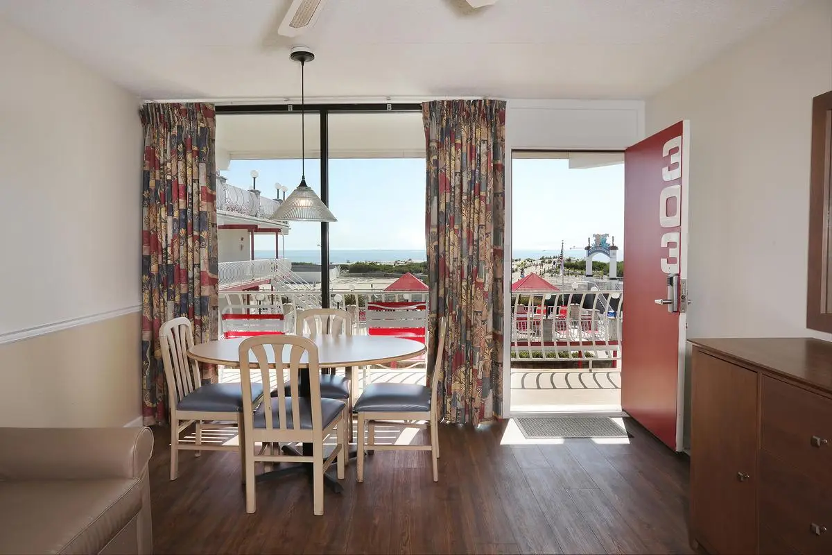 The living room of a Type 6 Family Ocean View Efficiency at the Matador, with a sofa bed, dining table and balcony door